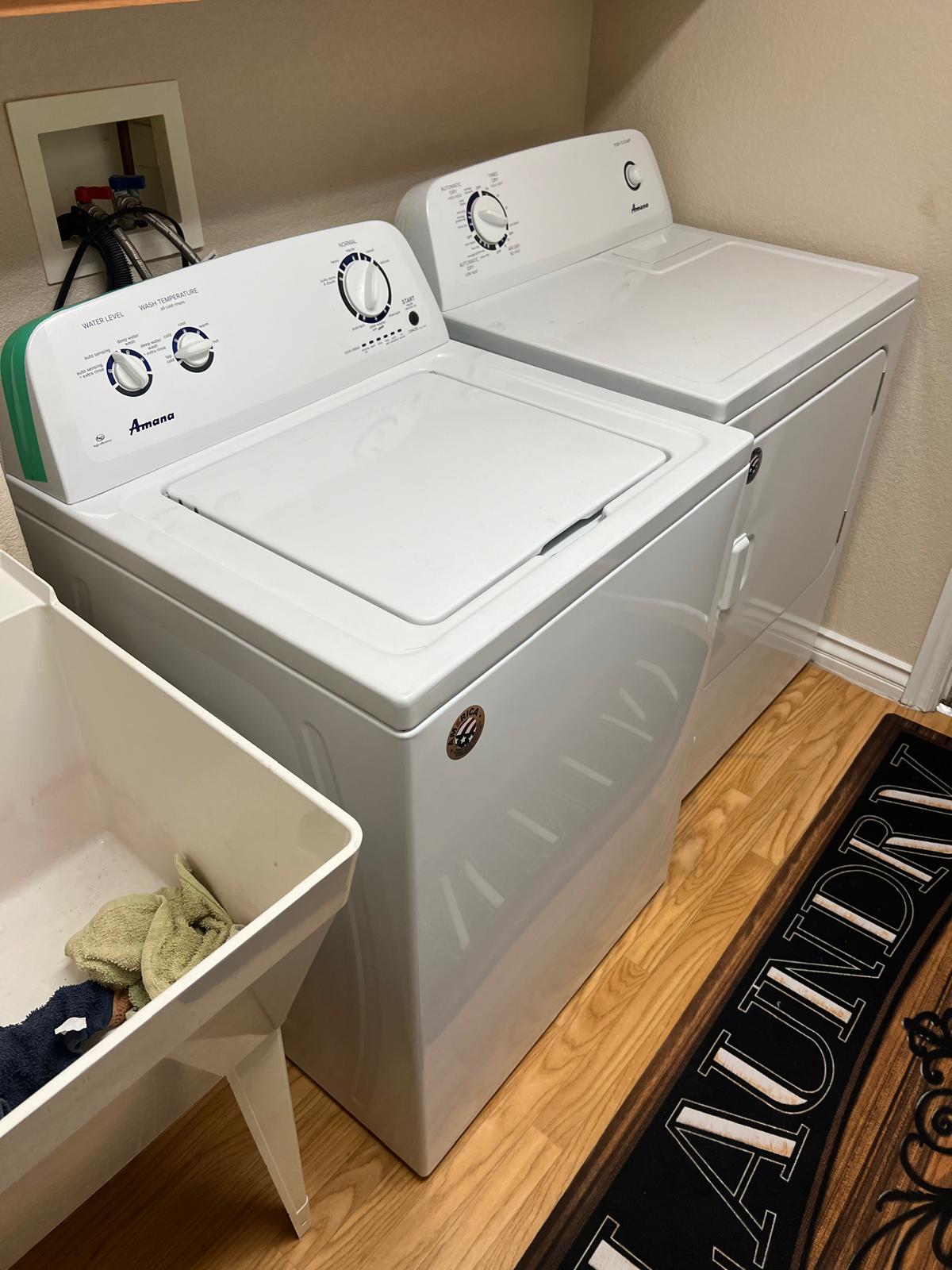White Amana top-load washer and matching dryer in a laundry room