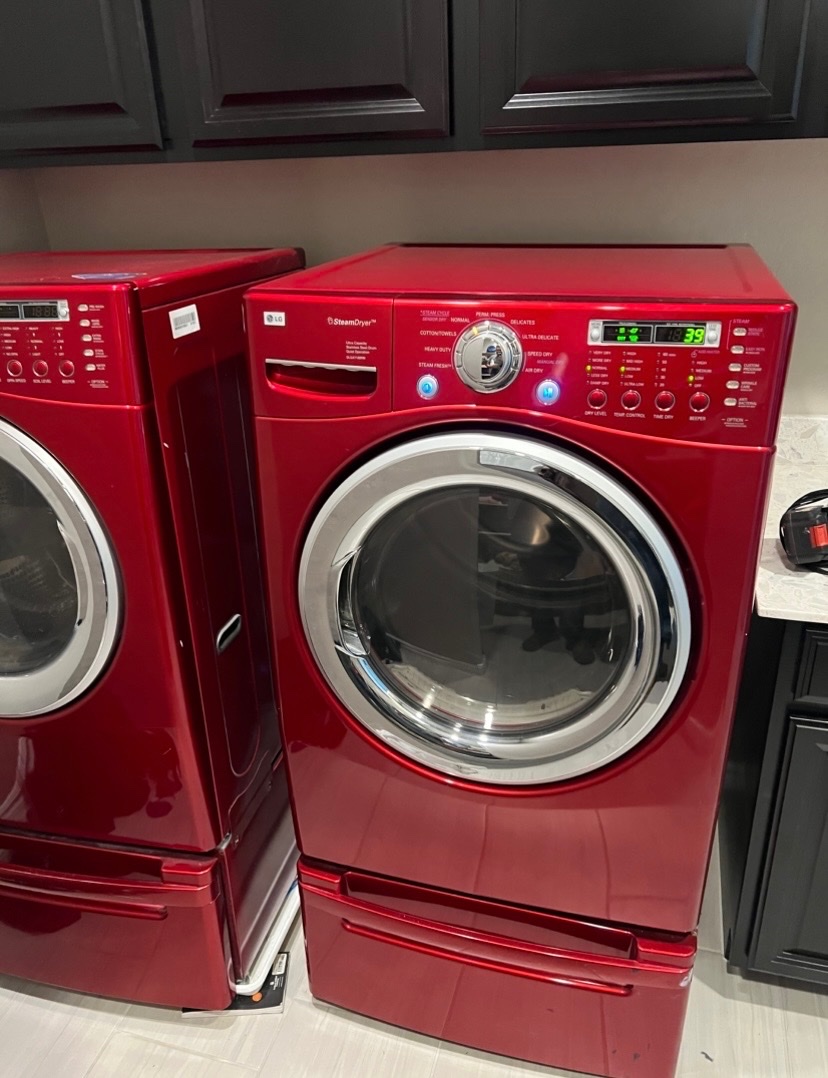 Red LG front-load washer and steam dryer set on pedestals