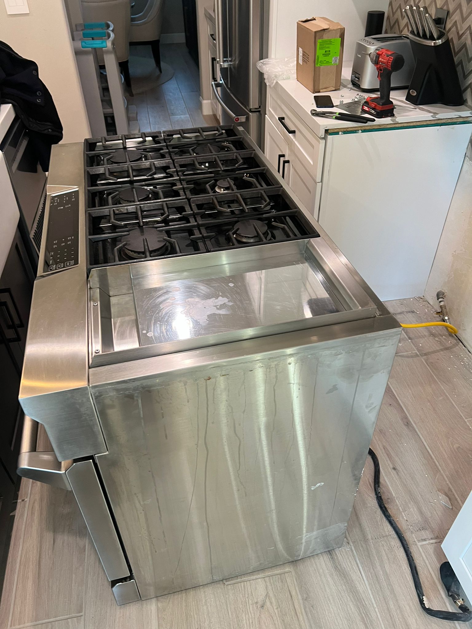 Stainless steel gas range with six burners pulled out during installation or repair